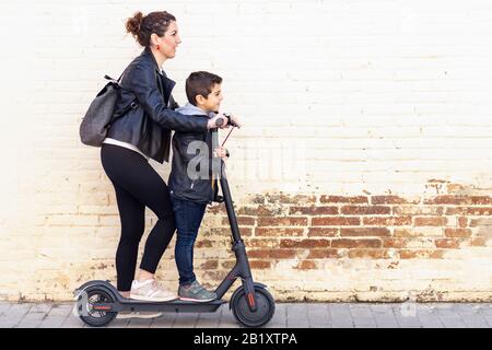 Mother and son riding an electric scooter Stock Photo