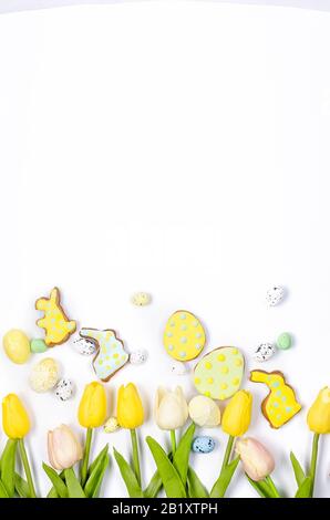 Easter homemade gingerbread cookies with icing, decorated eggs and tulips on a white background/ Happy easter concept. Copy space, flat lay, Template Stock Photo