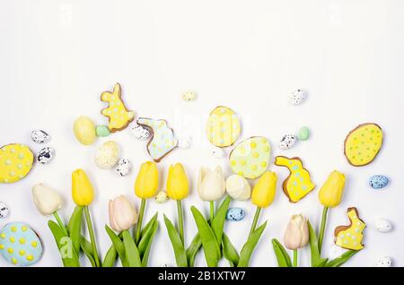 Easter homemade gingerbread cookies with icing, decorated eggs and tulips on a white background/ Happy easter concept. Copy space, flat lay, Template Stock Photo
