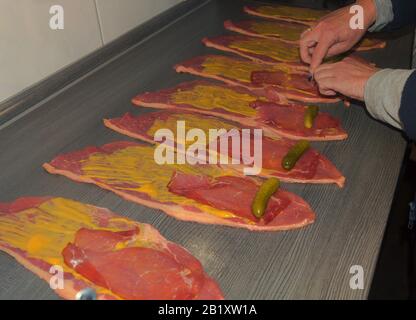 Preparation of fresh beef roulades, raw meat coated with mustard and onions. Stock Photo