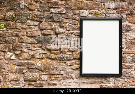 Blank noticeboard on an old stone wall outdoors Stock Photo