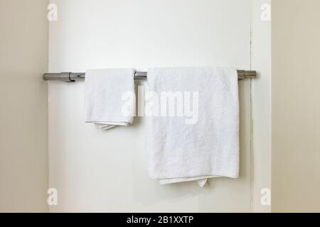 Basic white towels on a towel rail in a budget Motel bathroom, England, UK Stock Photo