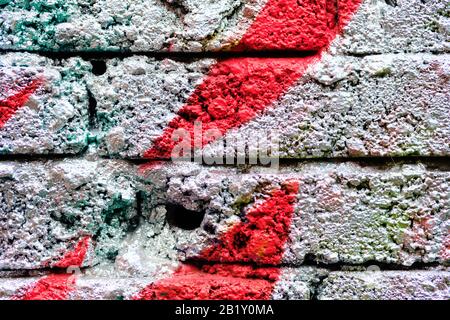 A crumbling brick wall as a texture painted silver color and red lines. Close up. Stock Photo