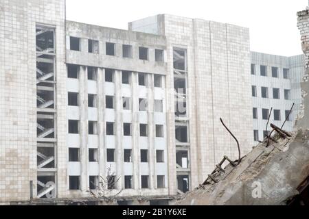 Fragments of concrete stones with protruding reinforcement on the background of the building in a foggy haze. Background. Stock Photo