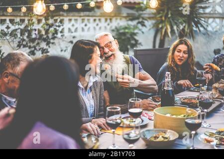 Happy family people having fun at barbecue dinner - Multiracial friends eating at bbq meal - Food, friendship, relationship and summer lifestyle conce Stock Photo