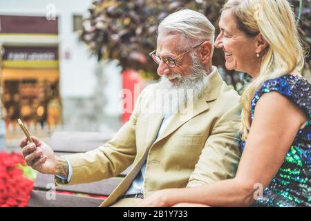 Happy senior couple having fun using smartphone app - Mature people using new trends technology - Joyful elderly lifestyle and love concept - Focus on Stock Photo