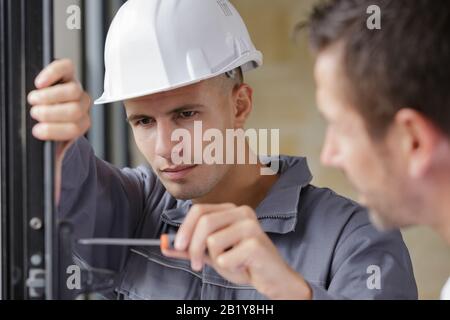 repairman fixing window with screwdriver Stock Photo