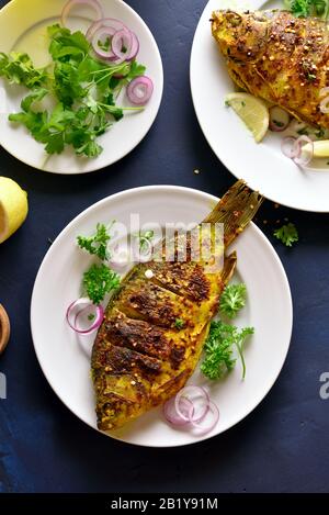 Grilled fish on plate over blue stone background. Top view, flat lay Stock Photo