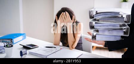 Businessman Giving Pile Of Folders To Female Assistant Stock Photo
