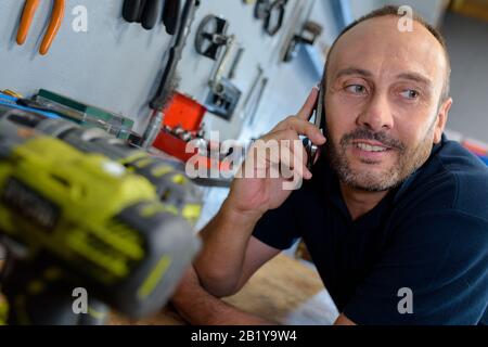 man using smartphone in workshop Stock Photo