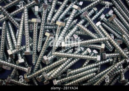 Hex head silver screws isolated on blue background. Stock Photo