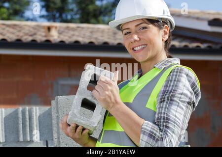 gorgeous female bricklayer holding a concrete block Stock Photo
