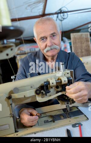 senior man using sewing machine Stock Photo
