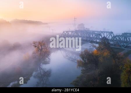 Aerial view of beautiful railroad bridge and river in fog in fall Stock Photo