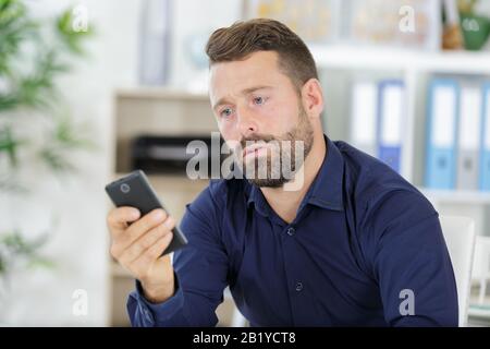 man using phone while sitting at desk in modern office Stock Photo