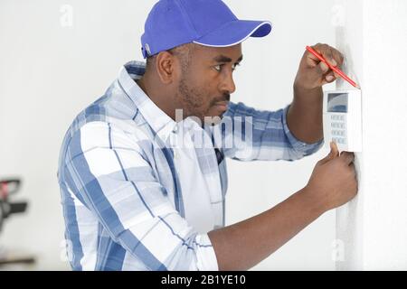 contractor installing keypad on the wall Stock Photo