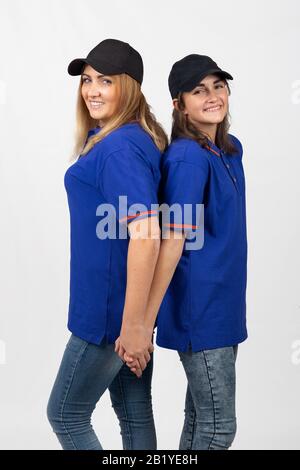 Two different-aged girls of European appearance in the same clothes stand with their backs to each other Stock Photo