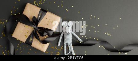Mouse is a Symbol of new year 2020. Toy mouse and stylish gift box with black bow on black background. New year and Christmas concept. Copy space. Ban Stock Photo