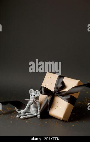 Mouse is a Symbol of new year 2020. Toy mouse and stylish gift box with black bow on black background. New year and Christmas concept. Copy space. Vet Stock Photo