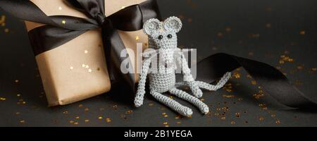 Mouse is a Symbol of new year 2020. Toy mouse and stylish gift box with black bow on black background. New year and Christmas concept. Copy space. Ban Stock Photo