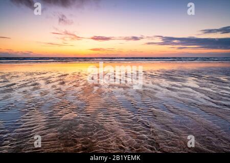 Westward Ho! Sunset with wet sand reflections on the beach, in North Devon UK Stock Photo