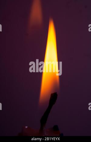 A Close Up of a Single Candle Flame and Wick on Coloured Background Stock Photo