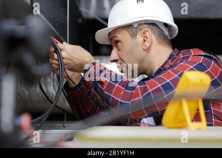 male electrician httesting power supply in roof space Stock Photo