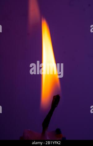 A Close Up of a Single Candle Flame and Wick on Coloured Background Stock Photo