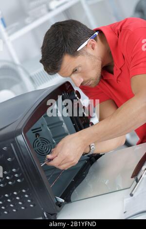 technician in overall installing oven Stock Photo