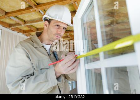 a man measuring window outdoors Stock Photo