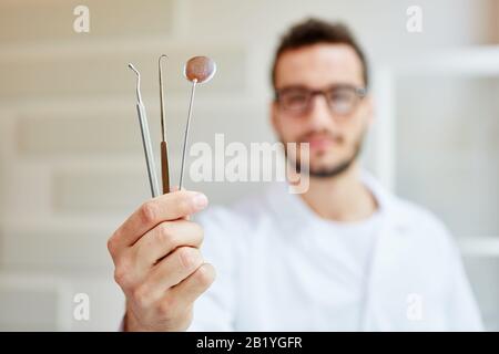 Young dentist with hand instruments in his dental office Stock Photo