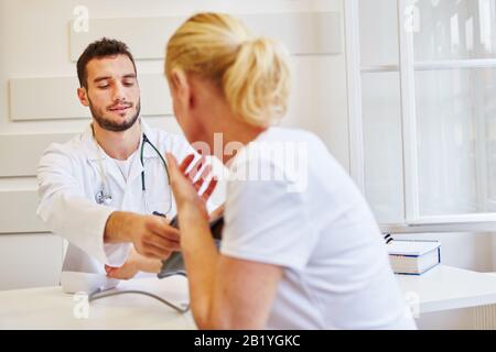 Doctor measures patient's blood pressure in his doctor's office Stock Photo