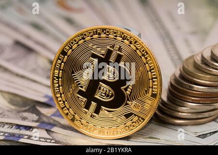 Gold bitcoin coin standing in front of dollar bills. Exchange bitcoin for a dollar concept .Physical version of Bitcoin Stock Photo