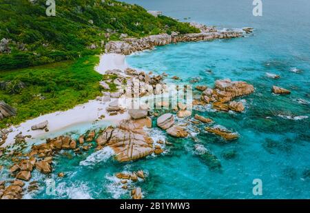 La Digue, Seychelles. Aerial view of secluded beach hidden surrounded by jungle foliage. White sand beach, turquoise ocean water and quaint granite Stock Photo