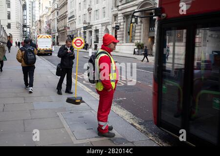 Council municipal worker waiting at a temporary bus stop in the City of London on 28th January 2020 in London, England, United Kingdom. The City of London is a historic financial district, home to both the great banking buildings. Modern corporate skyscrapers tower above the vestiges of medieval alleyways below. Stock Photo
