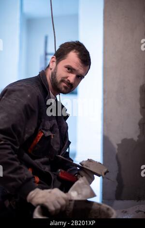 Construction worker plastering interior wall using cement plaster  Worker plastering the wall by concrete at the construction site Stock Photo