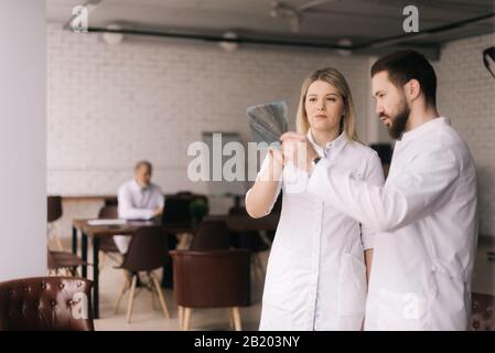 Two young dentists are examining the patient's jaw X-ray. Stock Photo