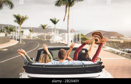 Happy friends having fun in convertible car on vacation - Young millennial people driving on cabriolet in summer holidays Stock Photo