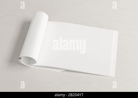 Blank horizontal right magazine page. Workspace with folded magazine mock up on white desk. Side view Stock Photo