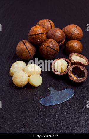 Organic macadamia nuts on black slate background, closeup. Stock Photo