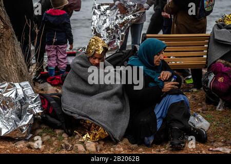 Lesbos, Greece. 28th Feb, 2020. Migrants from Afghanistan sit on a beach after their arrival on the Greek island of Lesbos. According to the state news agency Anadolu, a spokesman for the Turkish ruling party AKP has hardly concealed his threat to open the borders for refugees in the country. Credit: Angelos Tzortzinis/dpa/Alamy Live News Stock Photo