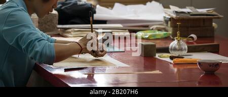 BEIJING, СHINA - JUNE 01, 2019: Traditional Chinese book and calligraphy restorer laboratory. Master hands at work close-up. Stock Photo