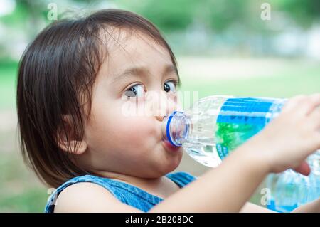 Asian toddler girl drinking water from the plastic water bottle. Stock Photo