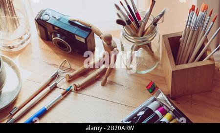 Photo of artist working table with accessories. Graphic designer desk essentials top view with wooden texture background. Set of artist accessories co Stock Photo