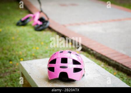 Pink helmet on the concrete bench in the park with pink push bike in the background. Stock Photo
