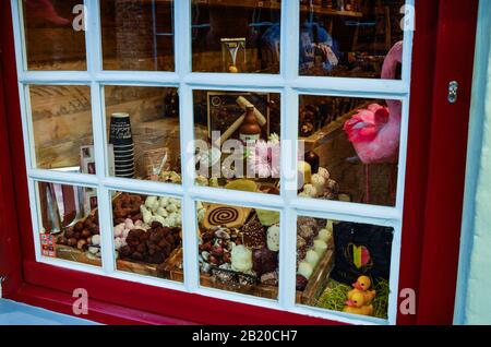 Bruges, Belgium. August 2019. Chocolate is a local specialty: from this window frame with a red frame with white finishes you can see various cocoa-ba Stock Photo