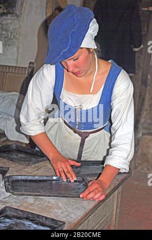 Tudor Woman in Kitchen Preparing Food on Table,  Reconstruction, Kentwell Hall, Long Melford Suffolk Stock Photo