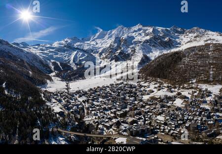 Aerial panorama of the famous Saas Fee village and ski resort by the Dom mountain, the tallest entirely in Switzerland in the alps on a sunny winter d Stock Photo