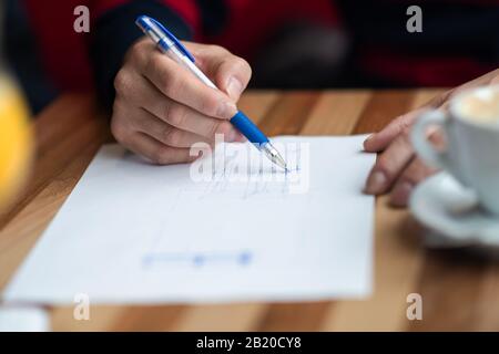 The hand of the designer with a pen, designing and sketching his idea for a furniture product Stock Photo