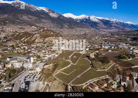 Aerial view of the city of Sierre in Canton Valais with vineyars, and a castle and medieval tower overlooking the Rhone valley in Switzerland on a sun Stock Photo